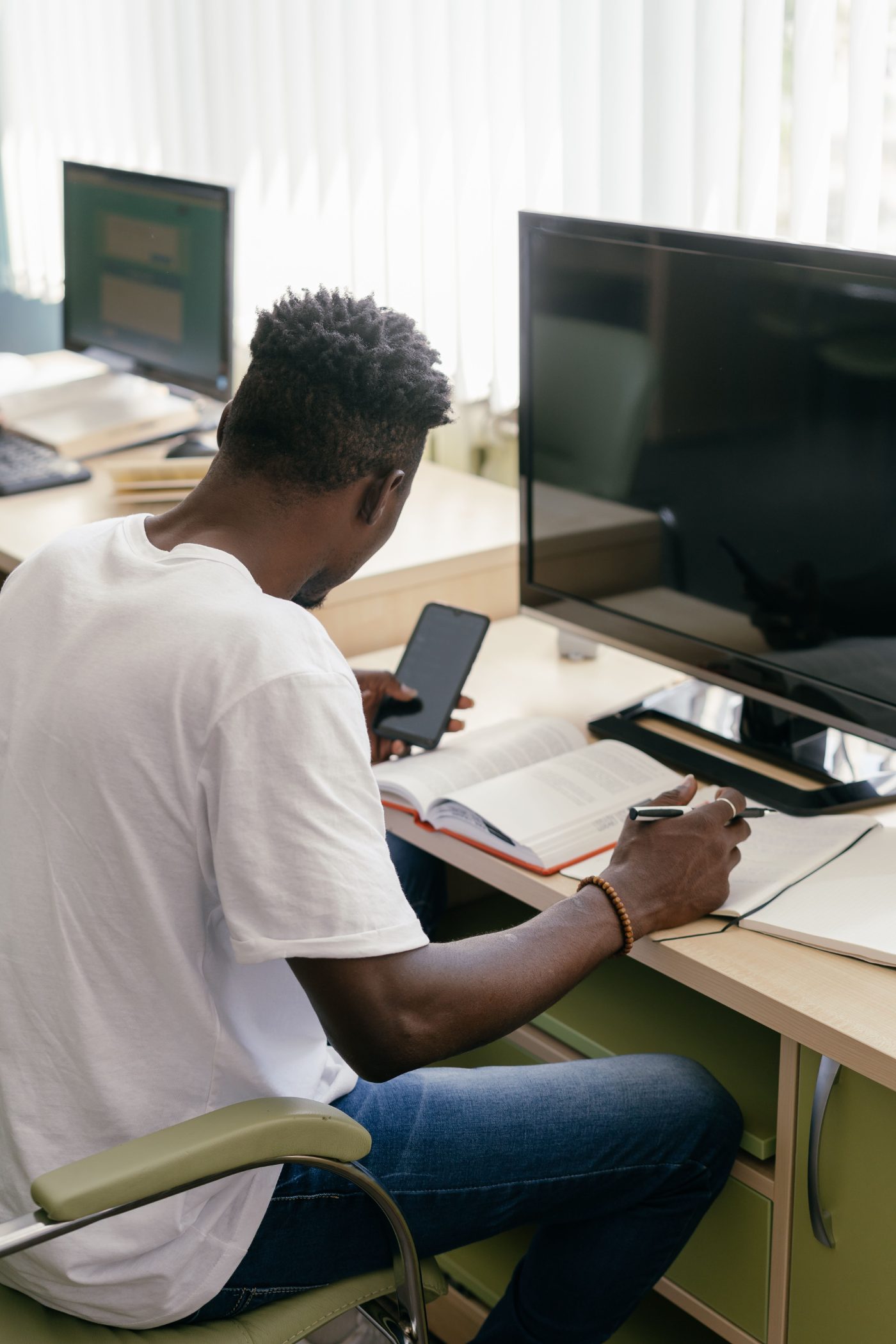A student at a desk with a phone, textbook and notebook